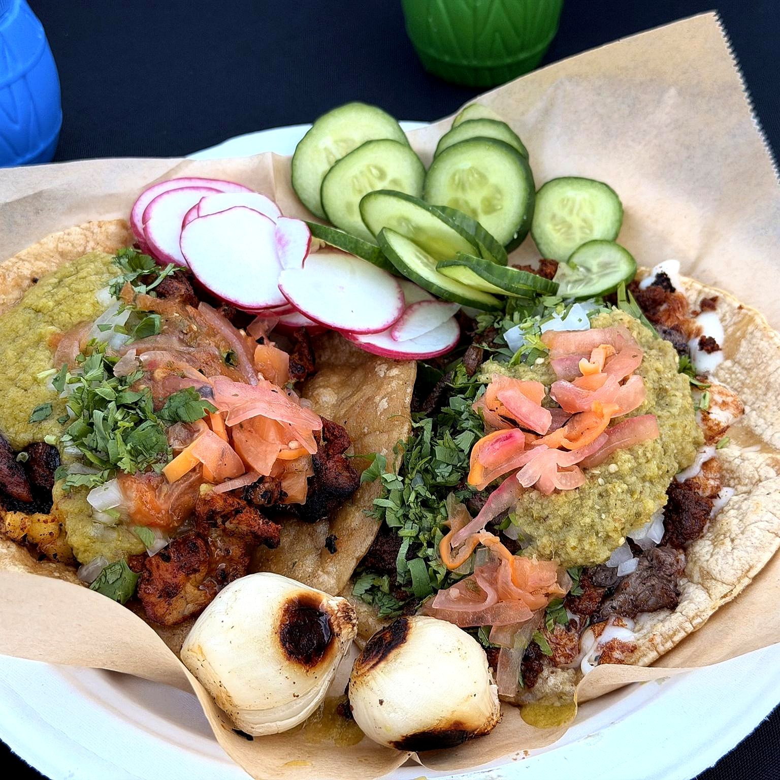 Two carne asada tacos plated with grilled onion